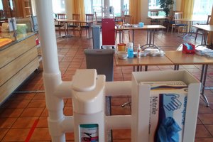 Handschuhe und Desinfektionsmittel auf Tischen verteilt